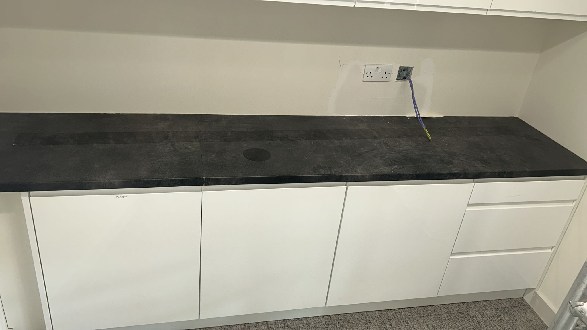 Counter with dark stone worktop and white base units